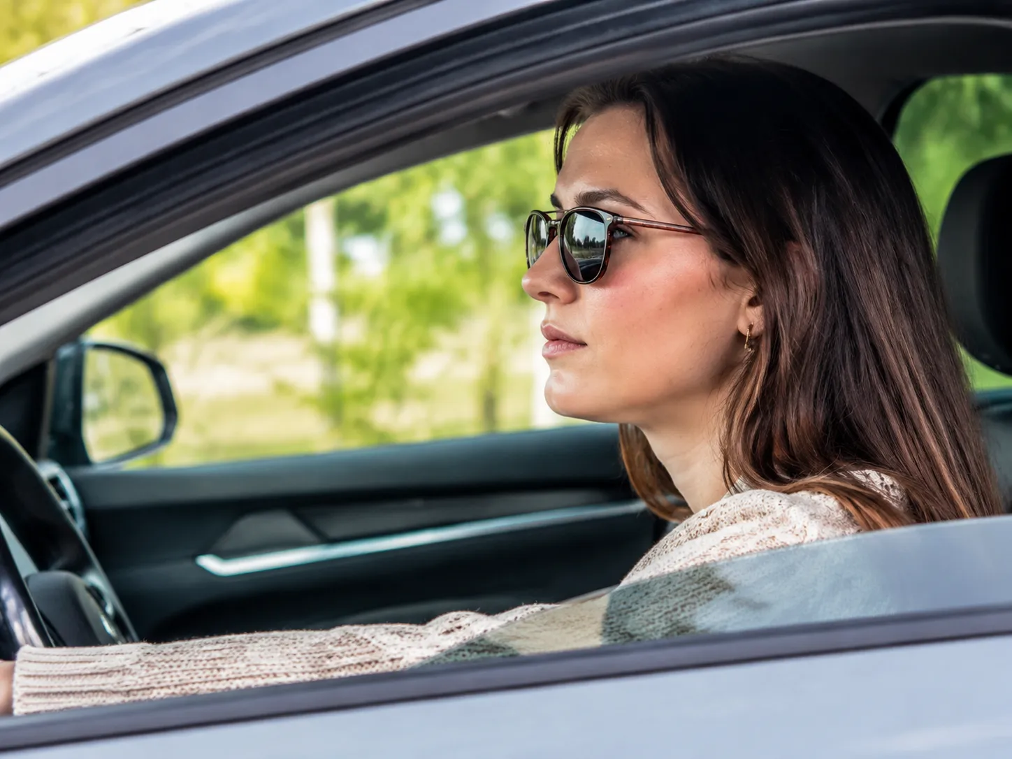 Woman with lupus wearing sunglasses while driving, illustrating the need for a medical window tint exemption